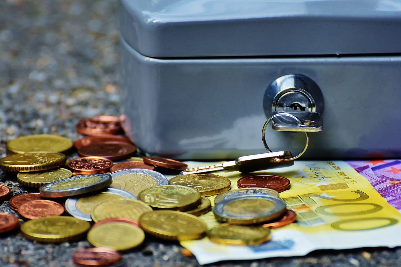 A small metal cash box holding coins and banknotes