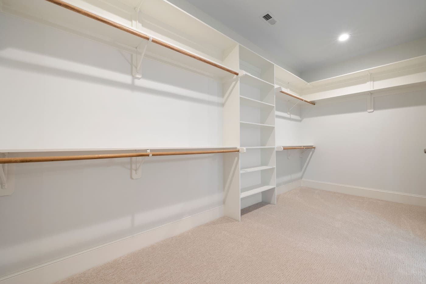 An empty walk-in closet with shelves and hanging rods