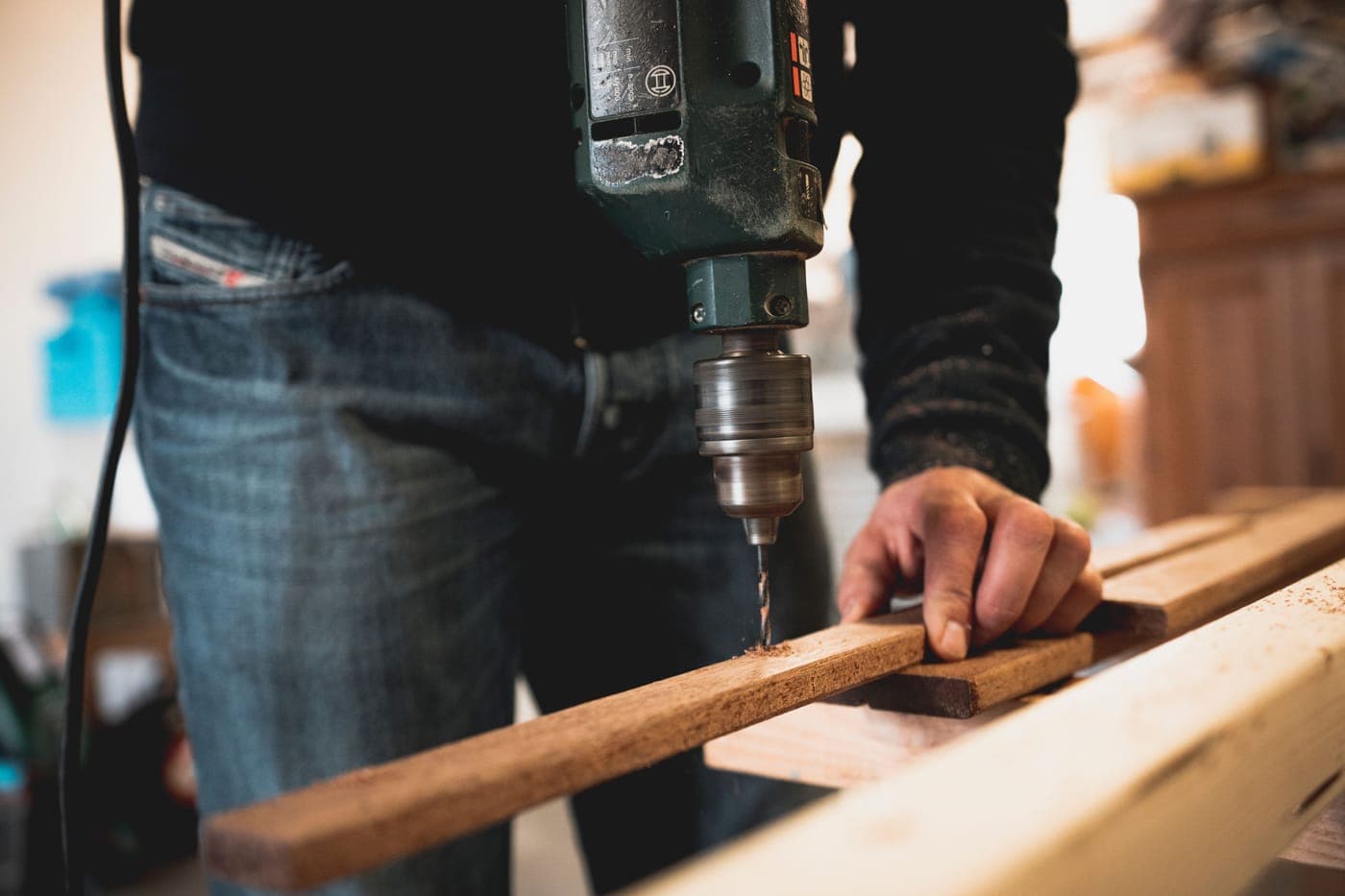A person drilling into a wooden plank with an electric drill
