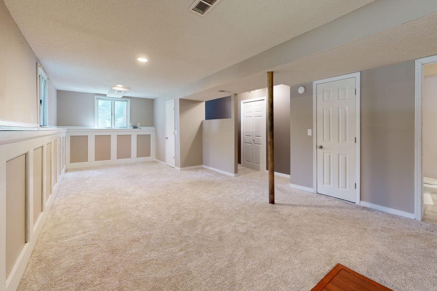 A clean, finished basement with carpet and recessed lighting