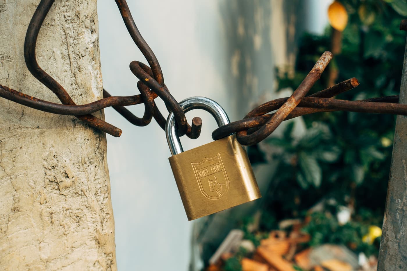 A brass padlock securing a wire on a concrete post
