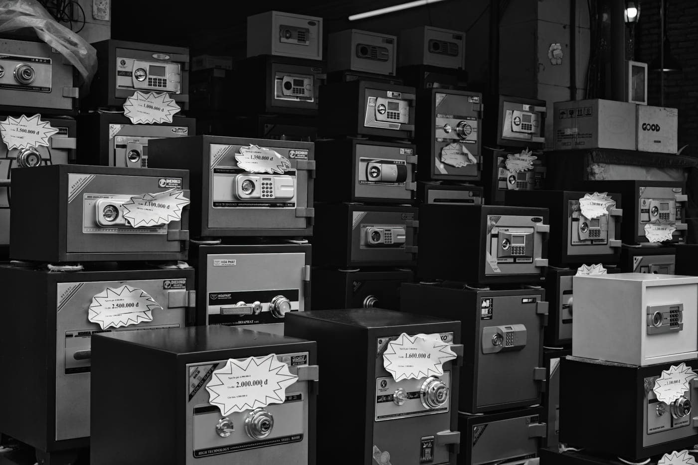 Black-and-white photo of safes stacked for sale in a store