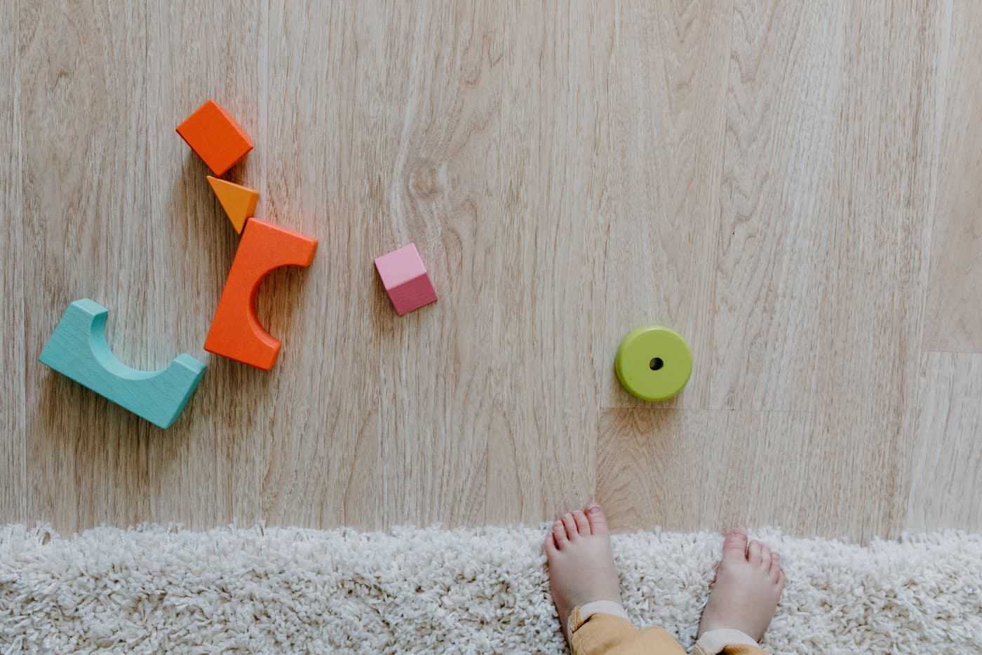 Colorful wooden blocks and a baby's feet on a carpet